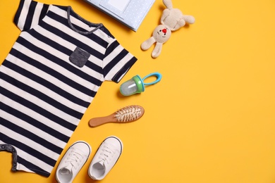 Photo of Flat lay composition with baby clothes and accessories on yellow background. Space for text