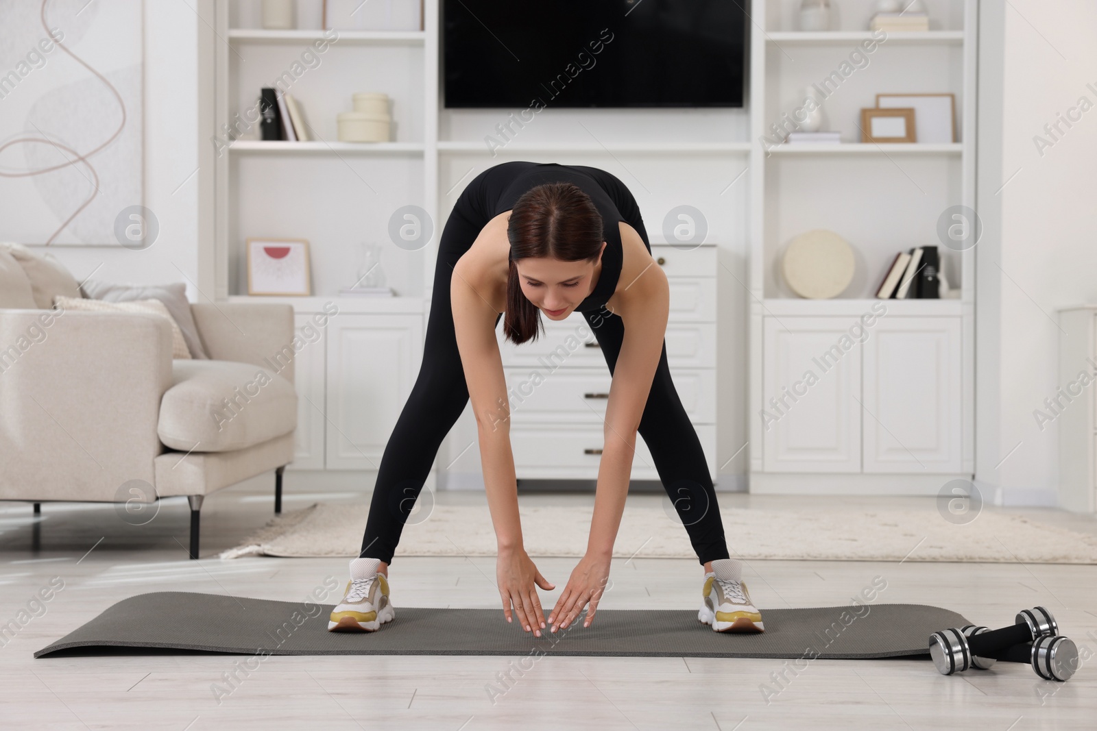 Photo of Morning routine. Sporty woman doing stretching exercise at home