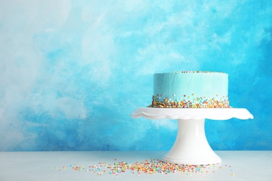 Fresh delicious birthday cake on stand against color background. Space for text