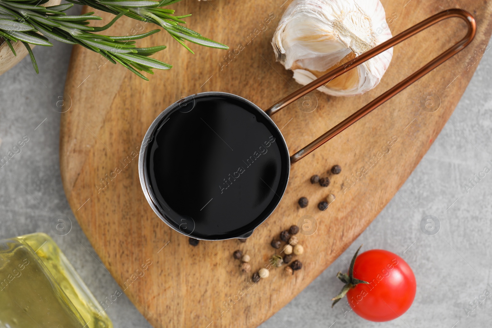 Photo of Organic balsamic vinegar and cooking ingredients on grey table, flat lay