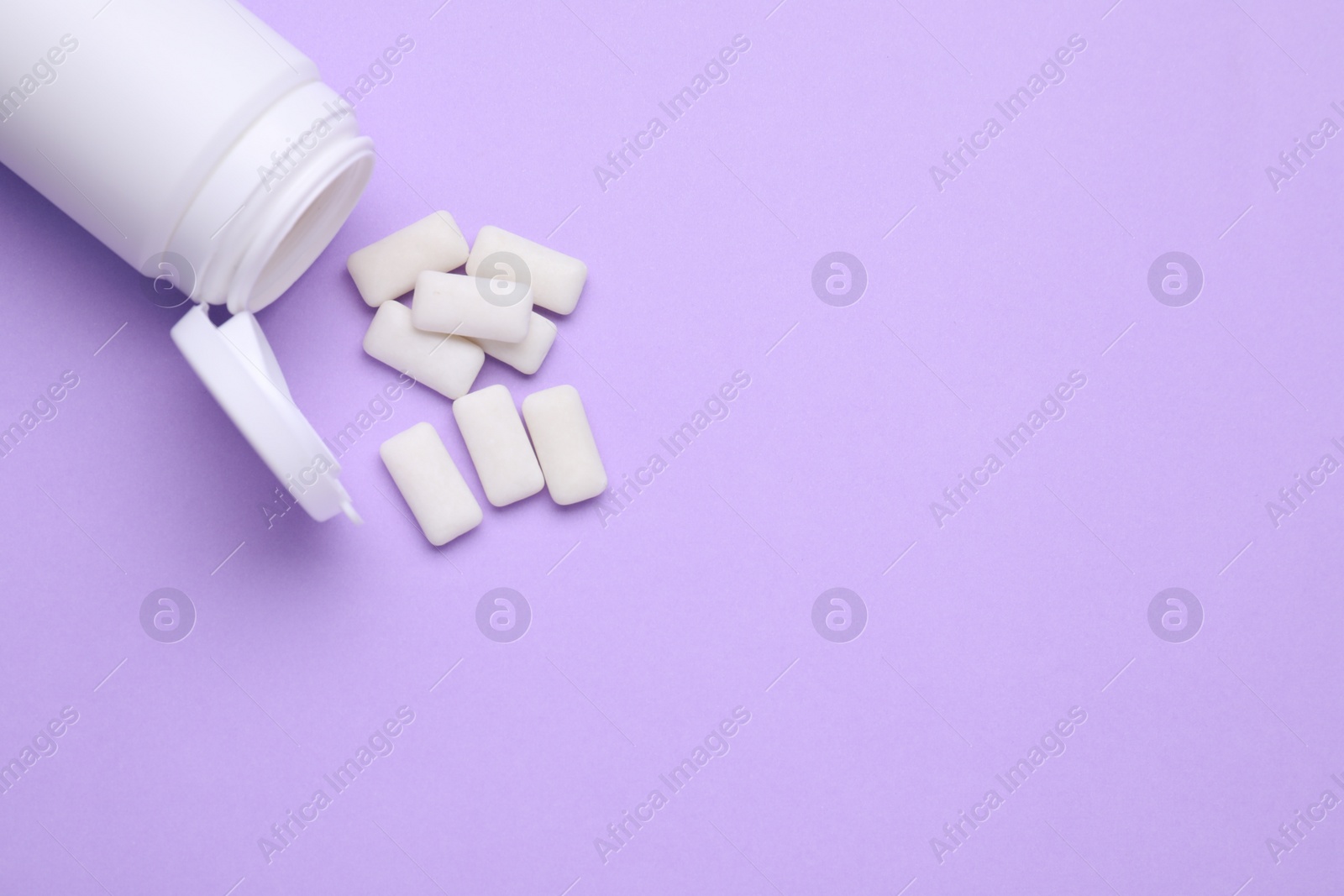 Photo of Jar with chewing gums on lilac background, flat lay. Space for text