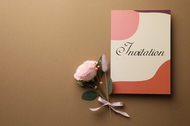 Photo of Card with word Invitation and beautiful flowers on beige background, flat lay. Space for text