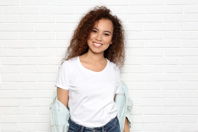 Young African-American woman with beautiful face near white brick wall