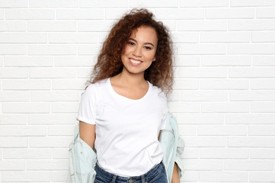 Photo of Young African-American woman with beautiful face near white brick wall