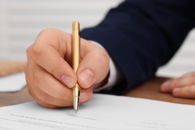 Man signing document at table, closeup view