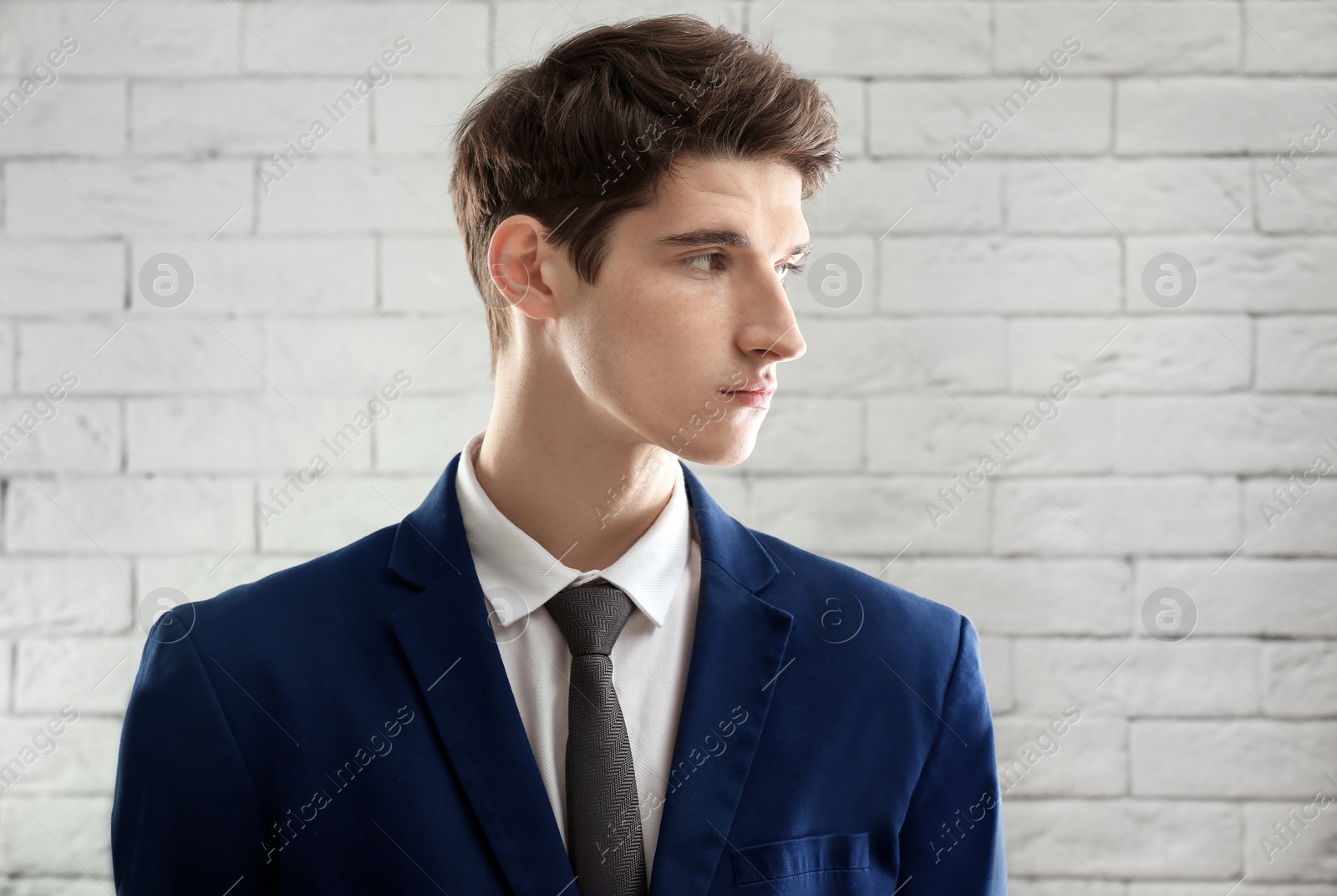 Photo of Portrait of young businessman with beautiful hair on brick wall background