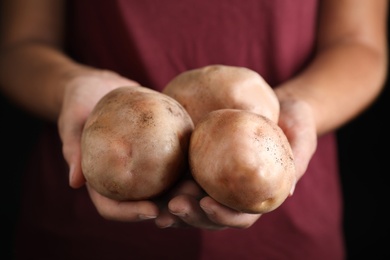 Photo of Farmer holding fresh ripe potatoes, closeup view