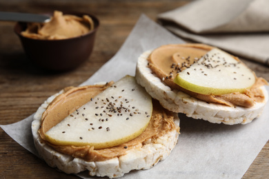 Photo of Puffed rice cakes with peanut butter and pear on wooden table