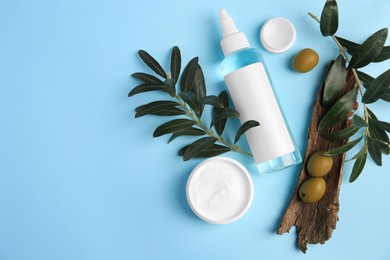 Flat lay composition with different cosmetic products and olives on light blue background. Space for text
