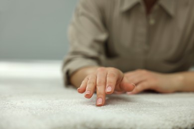 Woman touching soft white carpet indoors, closeup