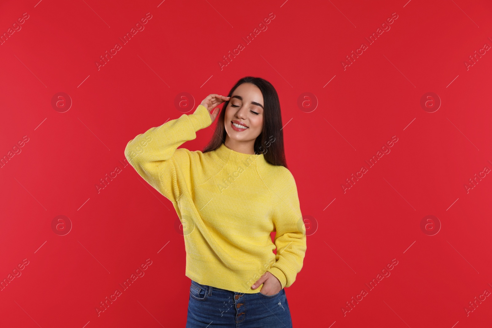 Photo of Beautiful young woman wearing yellow warm sweater on red background