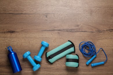 Photo of Turquoise weighting agents and sport equipment on wooden table, flat lay. Space for text