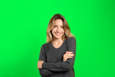 Image of Chroma key compositing. Pretty young woman smiling against green screen