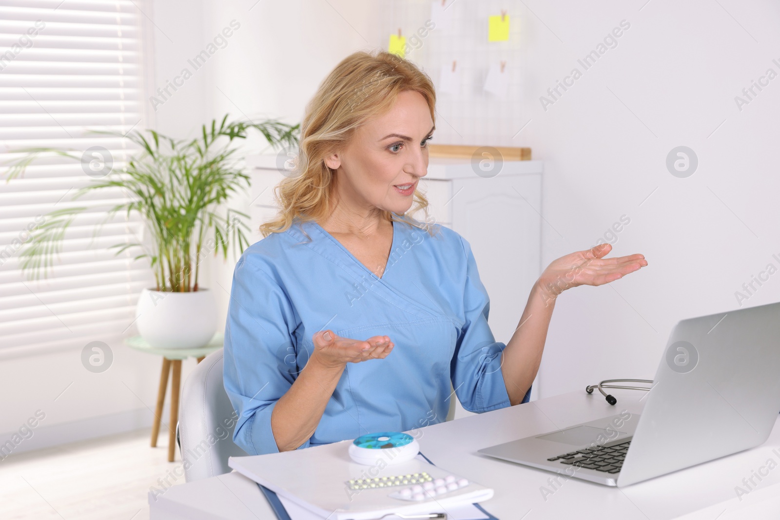 Photo of Doctor with laptop consulting patient in clinic. Online medicine concept