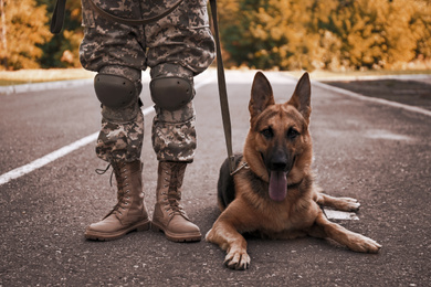 Image of Man in military uniform with German shepherd dog outdoors, closeup