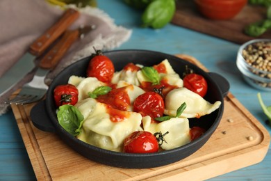 Photo of Tasty ravioli with tomato sauce served on blue wooden table
