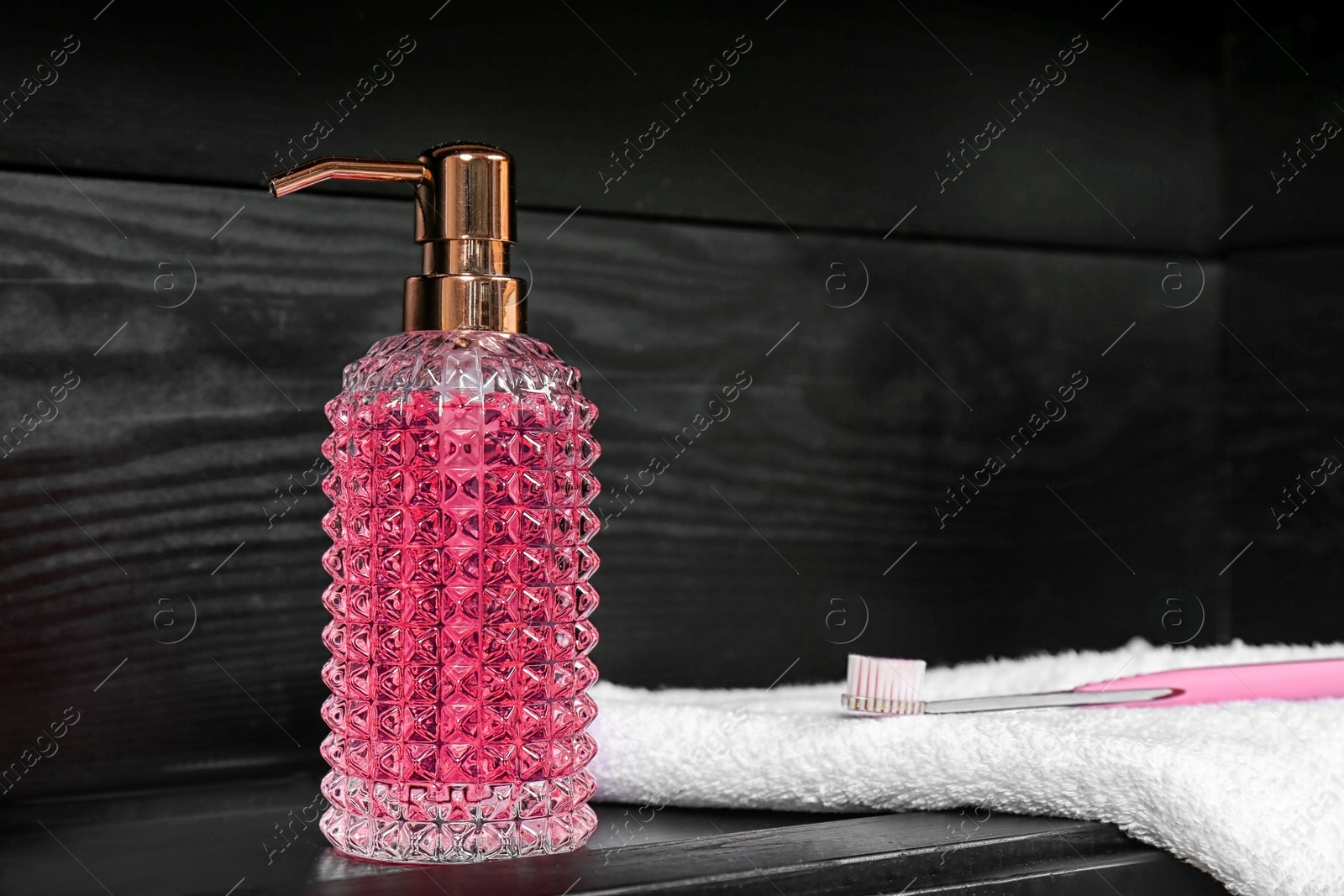 Photo of Soap dispenser, towel and toothbrush on table. Space for text