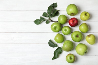 Photo of Red apple among green ones and space for text on wooden background, top view. Be different