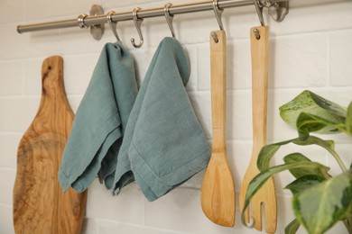 Photo of Clean towels and utensils hanging on rack in kitchen