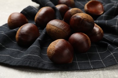 Photo of Roasted edible sweet chestnuts on light table, closeup