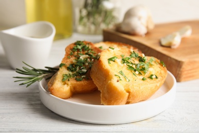 Photo of Plate with delicious homemade garlic bread on table