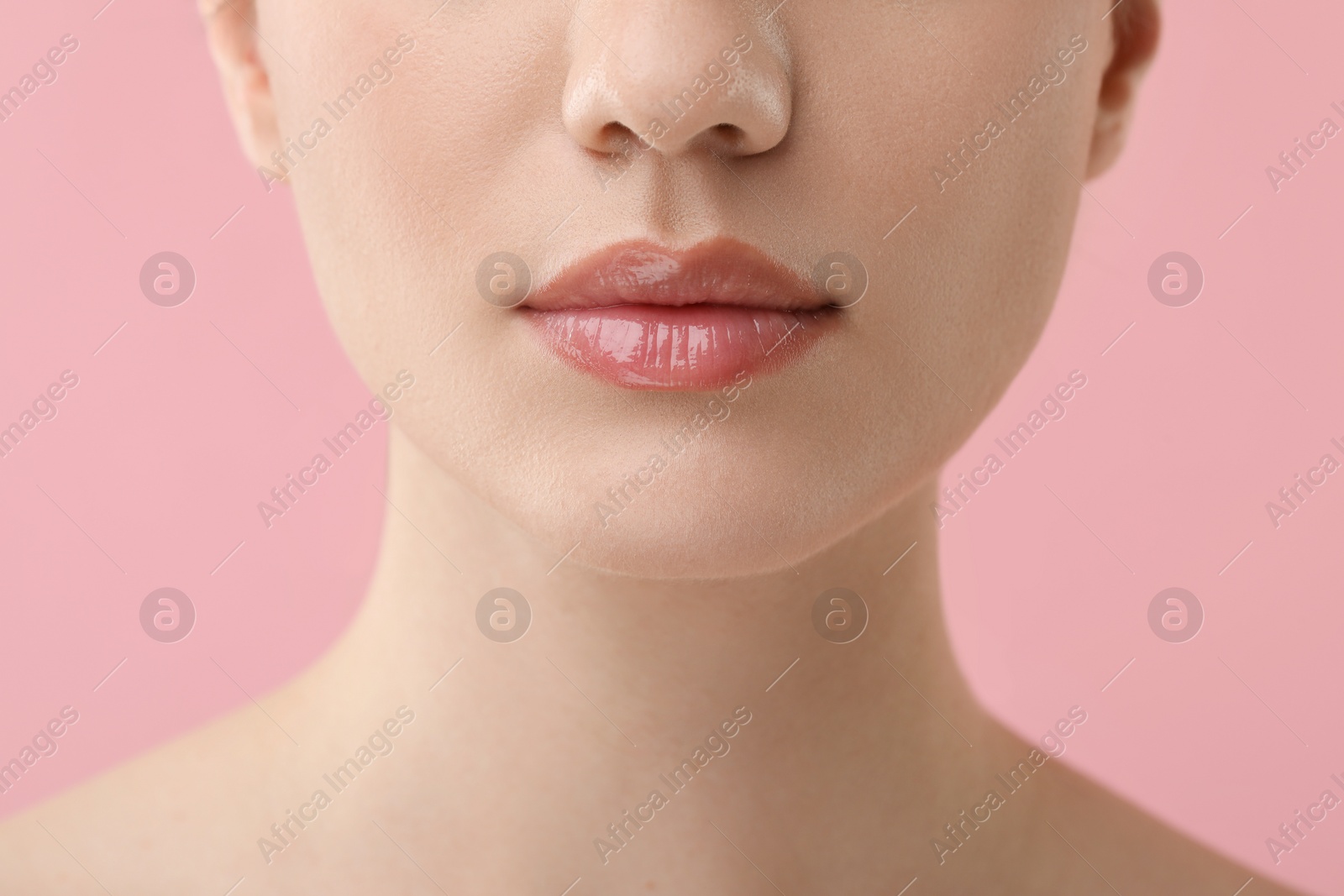 Photo of Woman wearing beautiful lip gloss on pink background, closeup