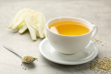 Photo of Aromatic fennel tea, seeds and fresh vegetable on grey table, closeup. Space for text