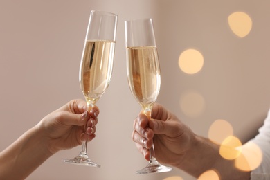 Photo of People clinking glasses of champagne against blurred background, closeup. Bokeh effect
