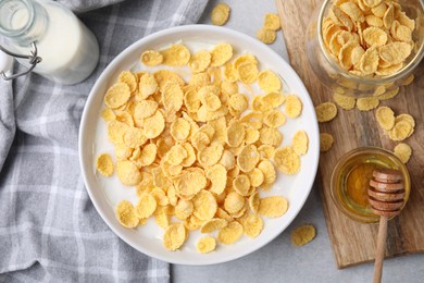 Photo of Breakfast cereal. Corn flakes and milk in bowl on light grey table, flat lay