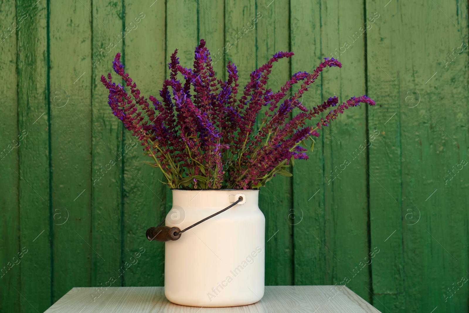 Photo of Beautiful bouquet with field flowers in can on white wooden table