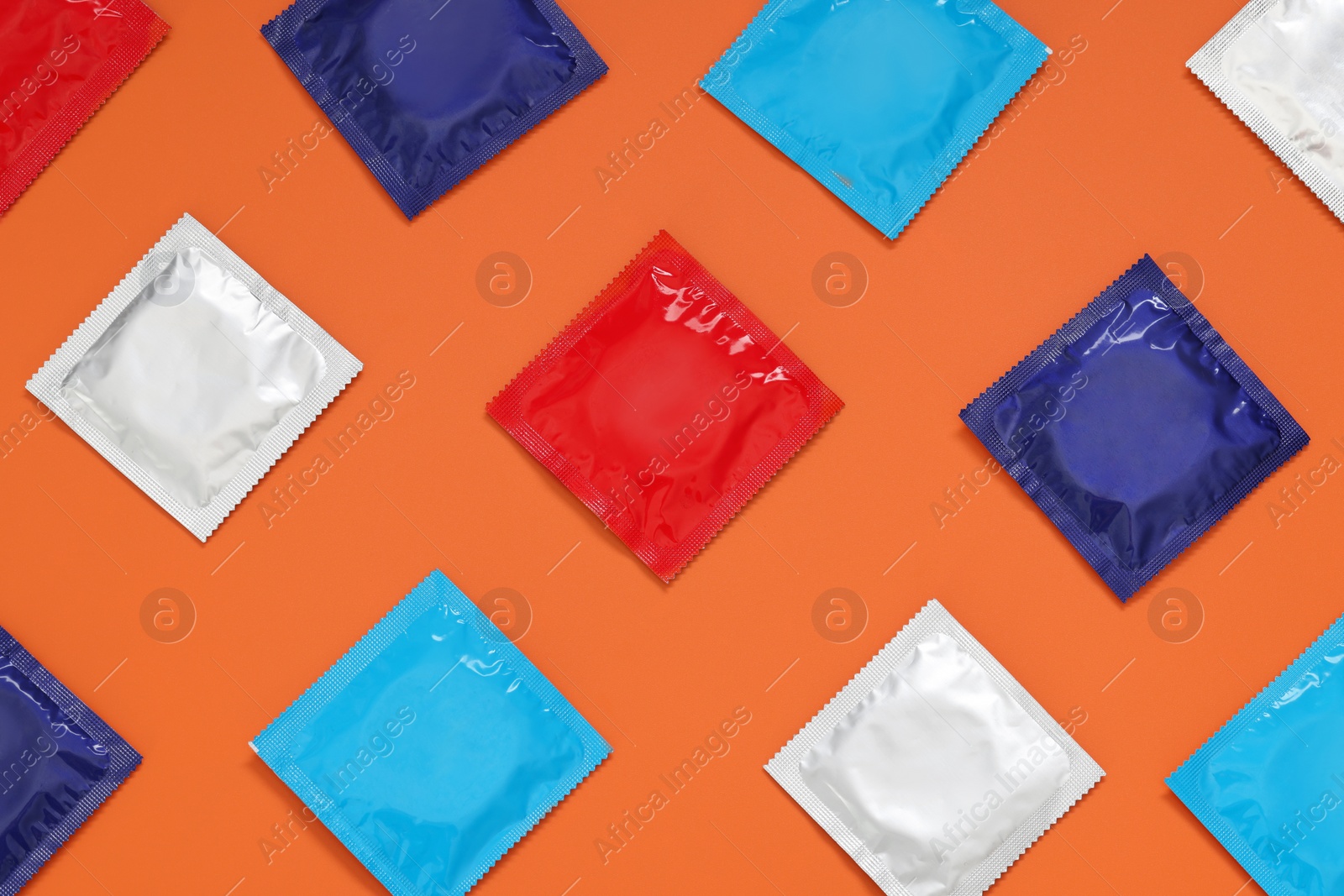 Photo of Packaged condoms on orange background, flat lay. Safe sex