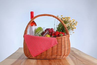 Picnic basket with wine and products on wooden table against white background