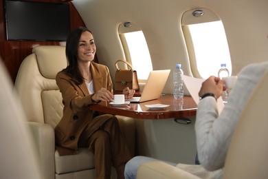 Photo of Colleagues working at table in airplane during flight