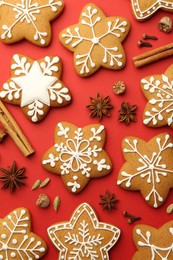 Photo of Tasty star shaped Christmas cookies with icing and spices on red background, flat lay