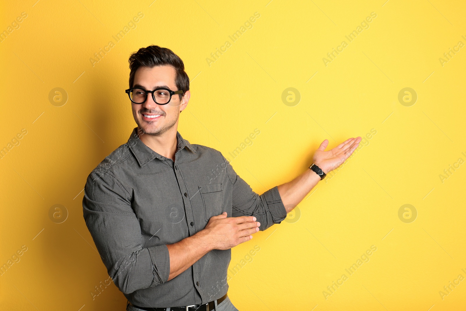 Photo of Young male teacher with glasses on yellow background. Space for text