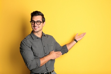 Photo of Young male teacher with glasses on yellow background. Space for text