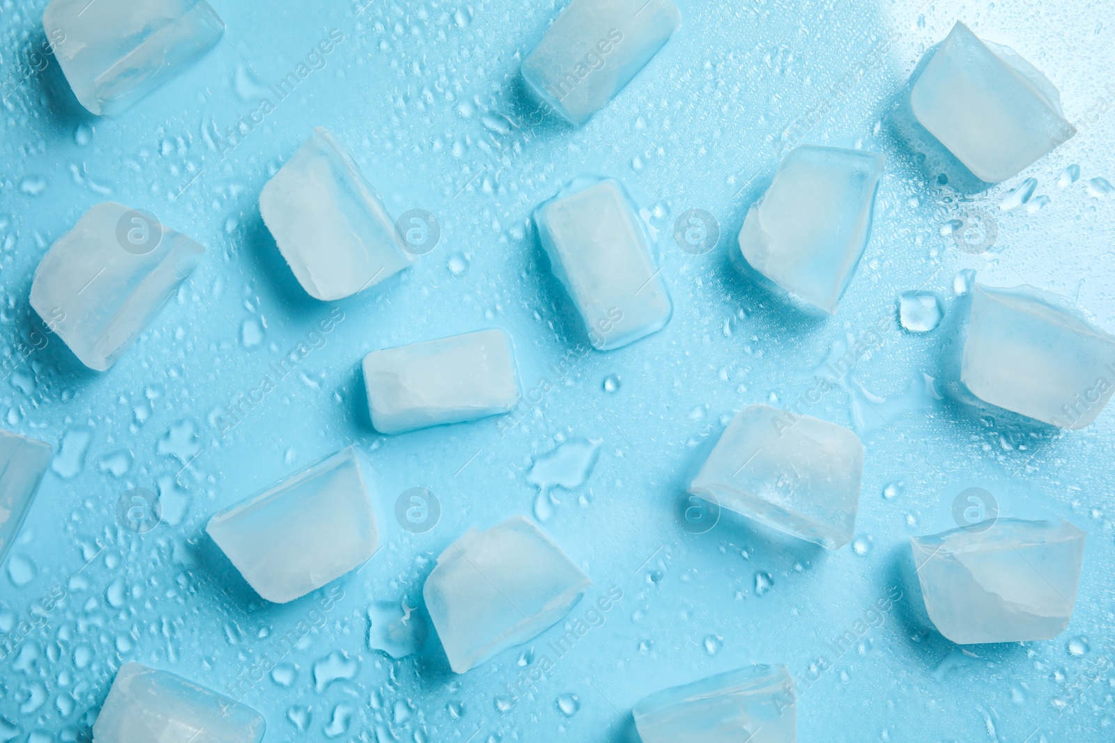 Photo of Cold ice and water drops on turquoise background, flat lay. Ingredient for refreshing drink