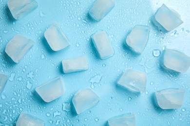 Cold ice and water drops on turquoise background, flat lay. Ingredient for refreshing drink