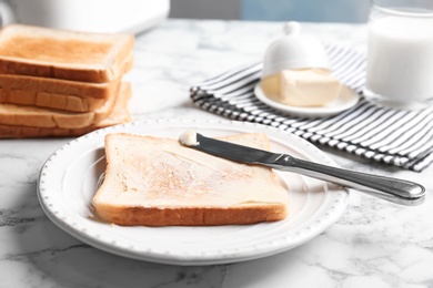 Photo of Plate with toasted bread and butter on table