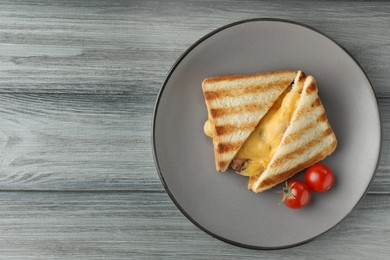 Tasty sandwiches with ham, melted cheese and tomatoes on grey wooden table, top view. Space for text