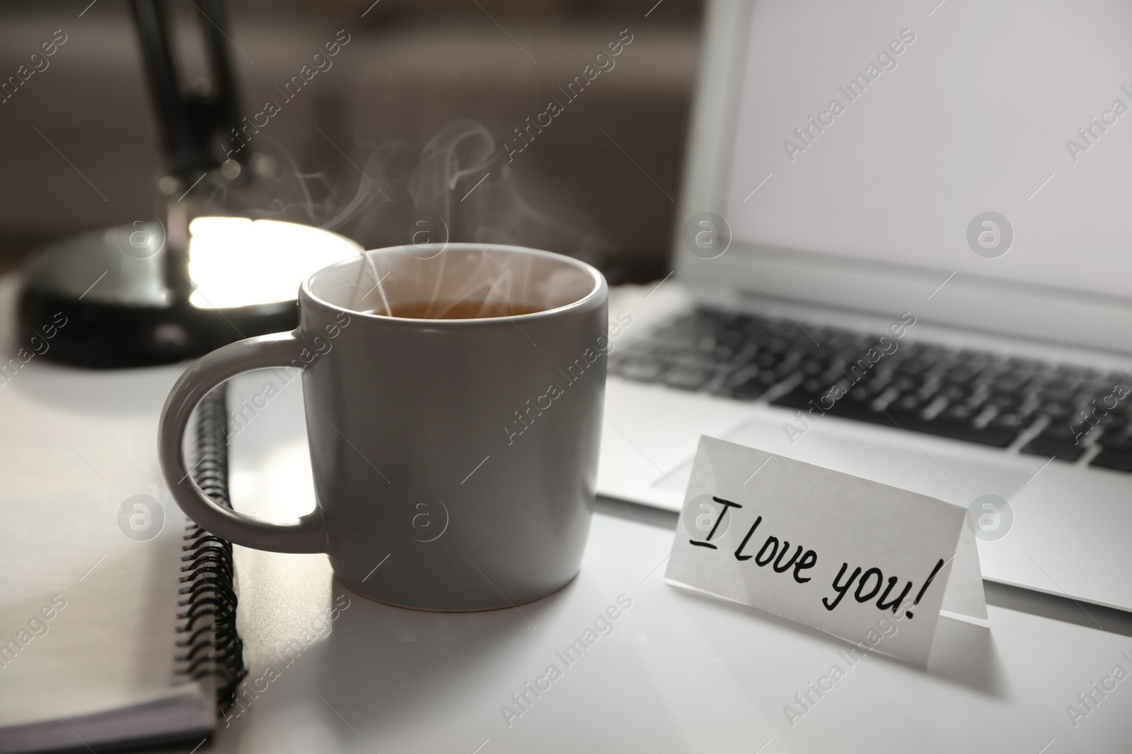 Photo of Note with handwritten text I Love You on workplace. Romantic message