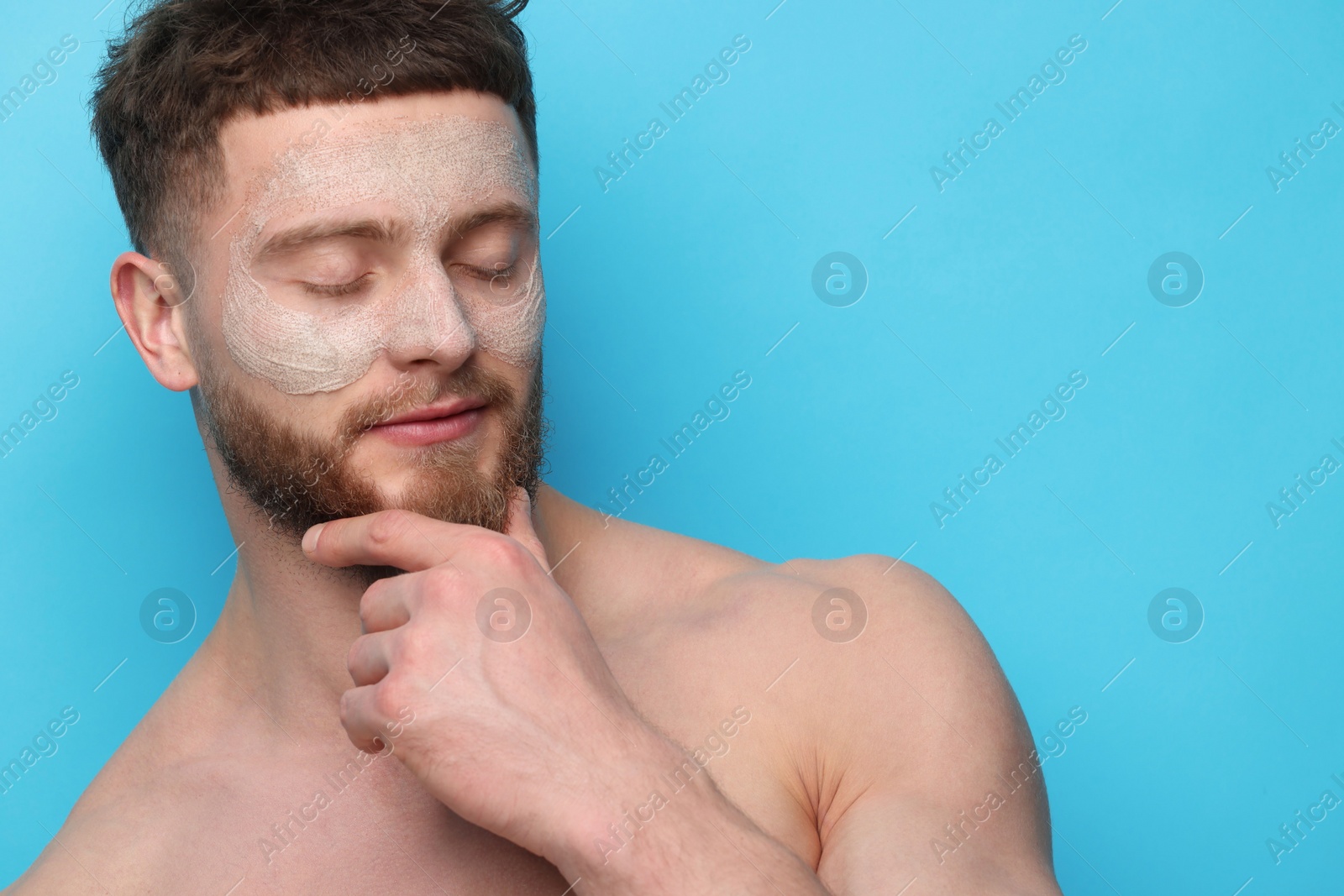 Photo of Handsome man with facial mask on his face against light blue background