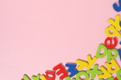Photo of Learning alphabet. Magnetic letters on pink background, flat lay. Space for text