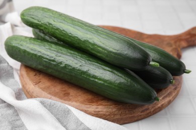 Photo of Fresh cucumbers on white tiled table, closeup