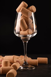 Photo of Glass with wine corks on dark table