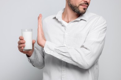 Man with glass of milk suffering from lactose intolerance on white background, closeup