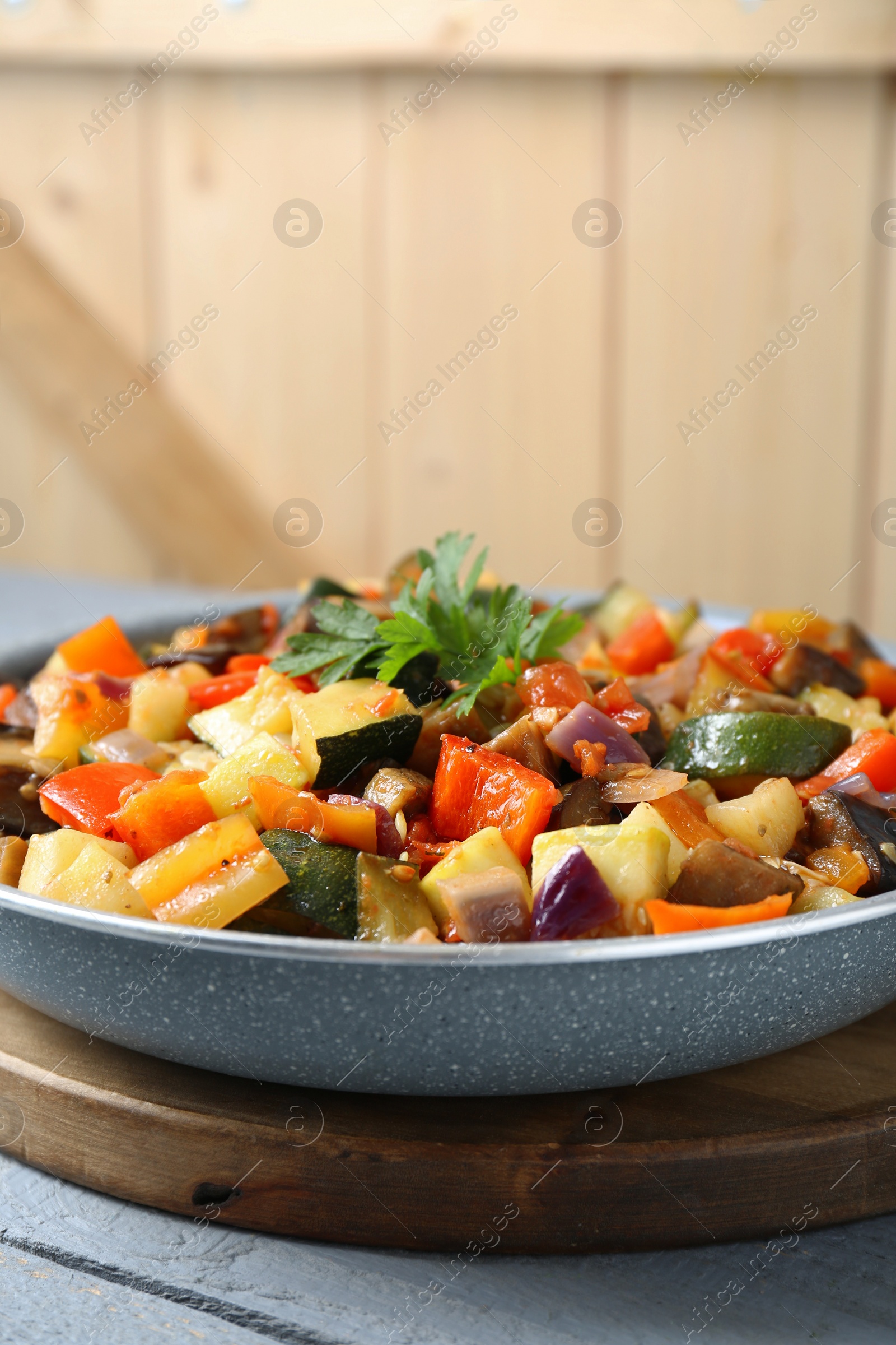 Photo of Delicious ratatouille in frying pan on grey table, closeup. Space for text