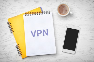 Notebook with acronym VPN on white wooden table, flat lay. Secure network connection