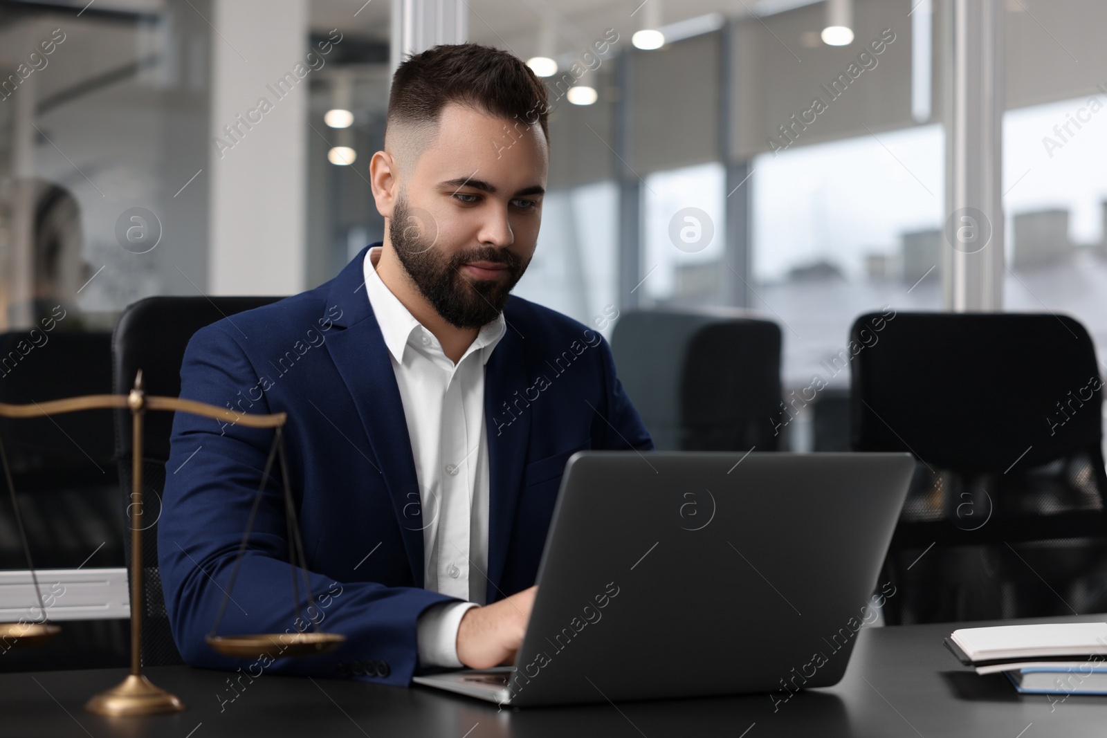 Photo of Serious lawyer working with laptop at table in office