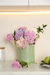 Photo of Beautiful hydrangea flowers in green can on light countertop